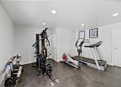 Thumbnail 12 of 12 - A home gym with a treadmill, elliptical trainer, and a weight machine.