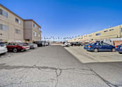 Thumbnail 8 of 12 - A parking lot with several cars and apartment buildings in the background.