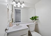 Thumbnail 6 of 16 - A white bathroom with a sink, toilet, and mirror.