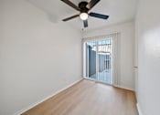 Thumbnail 8 of 16 - A room with a ceiling fan and sliding glass doors.