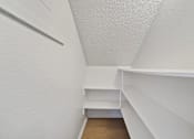 Thumbnail 9 of 16 - A white hallway with a bench and shelves.