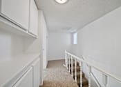 Thumbnail 10 of 16 - A white room with a staircase and a window.