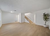 Thumbnail 4 of 16 - A room with wooden floors and a staircase.