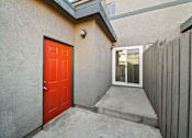 Thumbnail 14 of 16 - A red door is on the left side of a concrete staircase.
