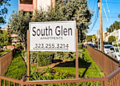 Thumbnail 2 of 20 - A sign for South Glen Apartments is displayed in front of a fence.
