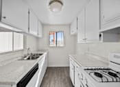 Thumbnail 9 of 20 - A kitchen with white cabinets and a white stove top oven.