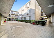 Thumbnail 5 of 8 - A courtyard with a concrete floor and apartment buildings in the background.