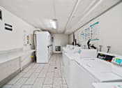 Thumbnail 7 of 8 - A laundromat with a row of washers and dryers.