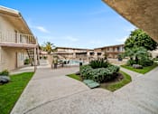 Thumbnail 8 of 17 - A concrete walkway leads to a pool surrounded by apartment buildings.