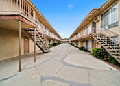 Thumbnail 10 of 17 - A long concrete walkway separates two rows of apartment buildings.