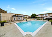 Thumbnail 15 of 17 - A large outdoor swimming pool surrounded by a fence and apartment buildings.