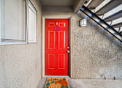 Thumbnail 3 of 9 - A red door with a welcome mat in front of it.