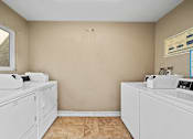 Thumbnail 7 of 9 - A laundry room with two washing machines and a dryer.