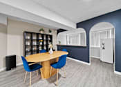 Thumbnail 14 of 15 - A dining area with a round table and blue chairs.