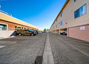 Thumbnail 4 of 9 - A parking lot with a yellow car and a white car.