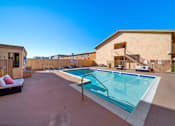 Thumbnail 5 of 9 - A swimming pool in a backyard with a building in the background.