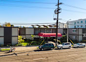 Thumbnail 1 of 15 - A parking lot with cars and a building in the background.