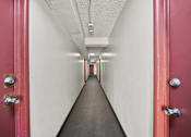 Thumbnail 12 of 15 - A long hallway with red doors on both sides.