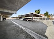 Thumbnail 3 of 6 - A parking lot with a red car parked in the shade.