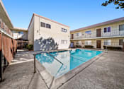 Thumbnail 4 of 6 - A swimming pool in front of a building with a blue sky in the background.