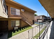 Thumbnail 4 of 9 - A sunny day at a residential area with apartment buildings and a metal fence.
