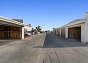 Thumbnail 1 of 7 - A long, empty parking lot with cars parked on the side.