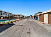 Thumbnail 5 of 7 - A long, empty street with apartment buildings on either side.