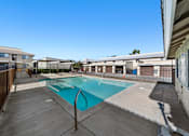 Thumbnail 6 of 7 - A swimming pool surrounded by a concrete deck and a metal fence.