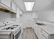 Thumbnail 4 of 8 - A modern kitchen with white cabinets and a white gas stove.
