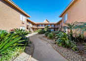 Thumbnail 5 of 13 - A pathway leads through a landscaped courtyard between two tan buildings.