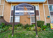 Thumbnail 1 of 13 - A sign for Terrace Pointe Apartments stands in front of a building.
