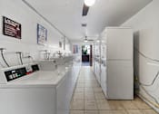 Thumbnail 12 of 13 - A laundromat with washers and dryers lined up.