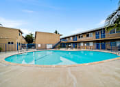 Thumbnail 2 of 12 - A large outdoor swimming pool surrounded by a fence.