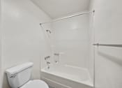 Thumbnail 19 of 20 - A white toilet and bathtub in a bathroom.