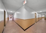 Thumbnail 14 of 20 - A long hallway with doors on both sides and an exit sign above.