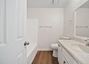 Thumbnail 10 of 14 - A white bathroom with a toilet, sink, and mirror.