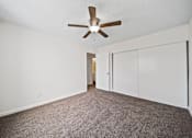Thumbnail 9 of 14 - A room with a ceiling fan and carpeted floor.