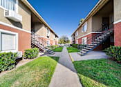 Thumbnail 11 of 14 - A pathway leads between two rows of apartment buildings.