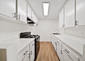 Thumbnail 5 of 14 - A kitchen with white cabinets and a black stove top oven.