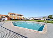 Thumbnail 12 of 14 - A small pool in a concrete area with a building in the background.