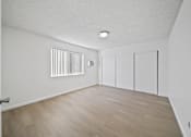Thumbnail 11 of 14 - A room with a white ceiling, a radiator on the wall, and a wooden floor.