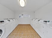 Thumbnail 13 of 14 - A laundromat with a row of washers and dryers.