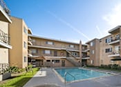 Thumbnail 3 of 5 - A large apartment complex with a pool in the middle.