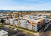 Thumbnail 1 of 14 - A view of a residential area with apartment buildings and cars parked on the street.