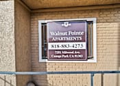 Thumbnail 3 of 14 - A sign for Walnut Pointe Apartments is on a building.