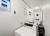 Thumbnail 14 of 14 - A white washing machine and dryer in a small laundry room.