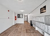 Thumbnail 12 of 14 - A long hallway with a sign on the wall and mailboxes on the right.
