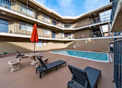 Thumbnail 7 of 14 - A pool area with a red umbrella and black lounge chairs.