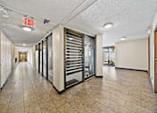 Thumbnail 3 of 6 - A long hallway with a red exit sign on the ceiling.
