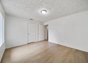 Thumbnail 2 of 18 - A room with white walls and wooden flooring with a window on the left side.